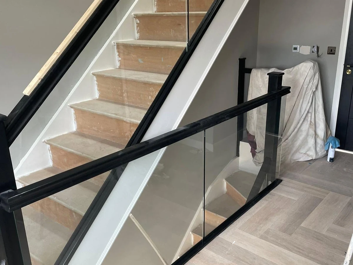 Frameless glass balustrade staircase with black frame and landing run installed by Farnham Glass Balustrades