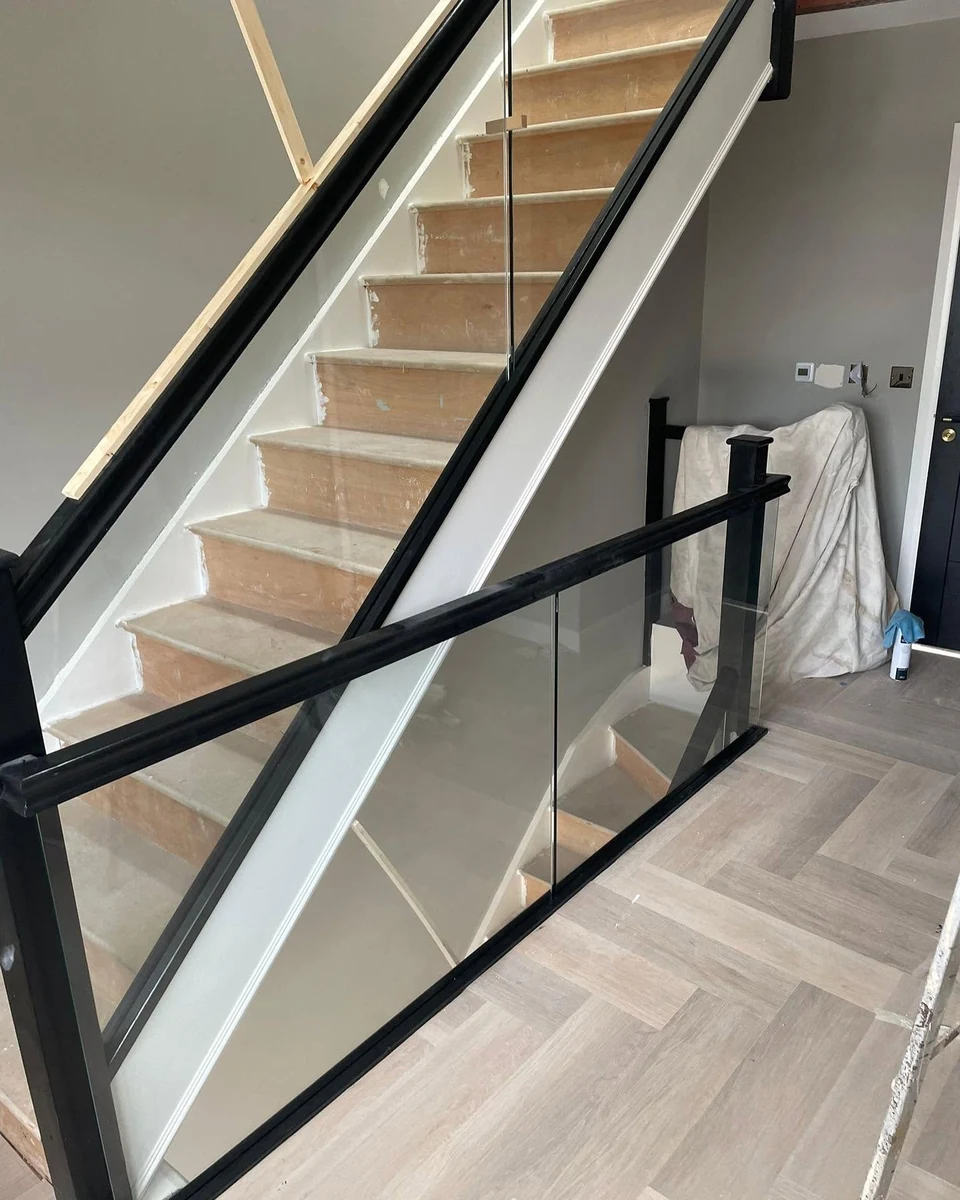 Frameless glass balustrade with black frame on staircase landing in Farnham