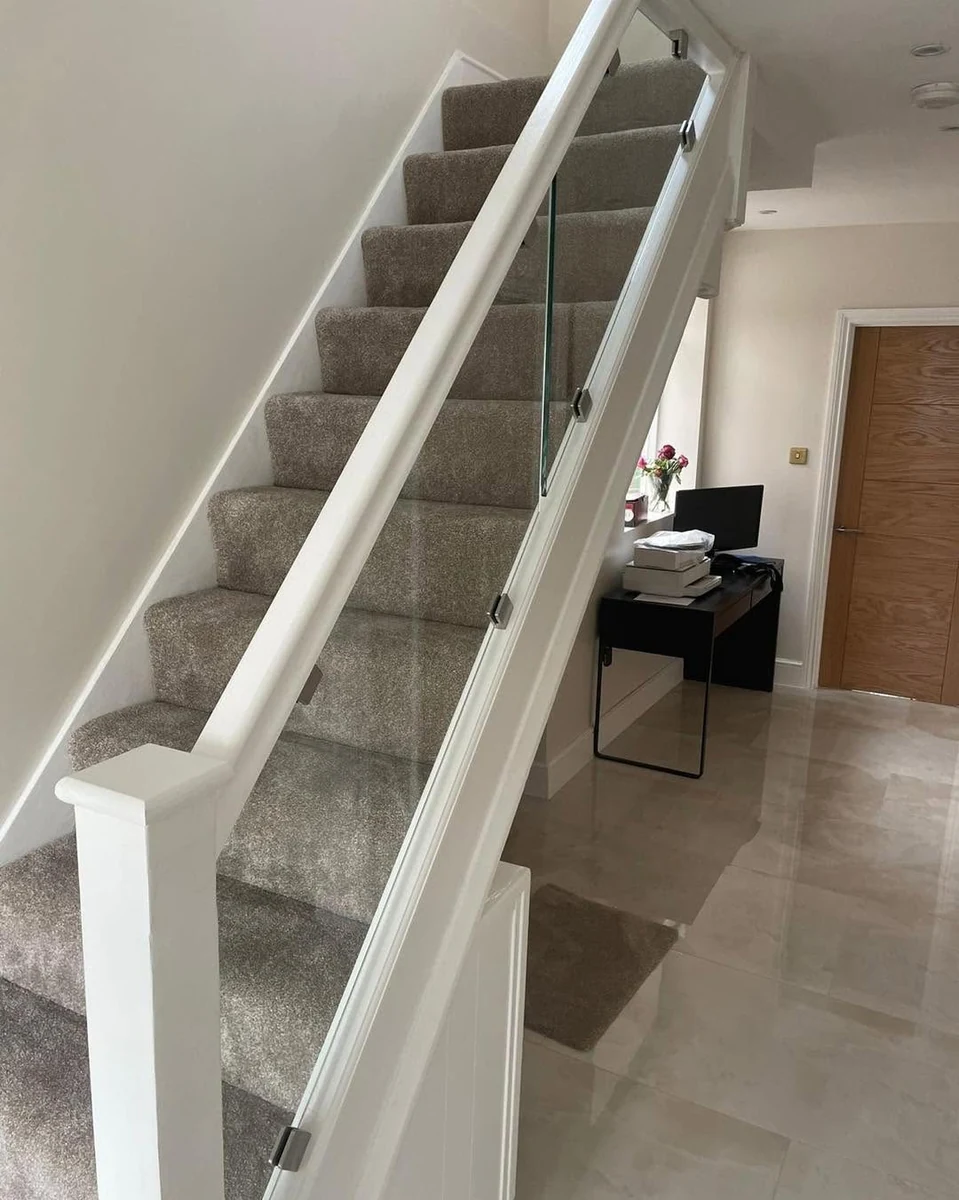 Bright hallway with frameless glass balustrade staircase runner installed in Farnham